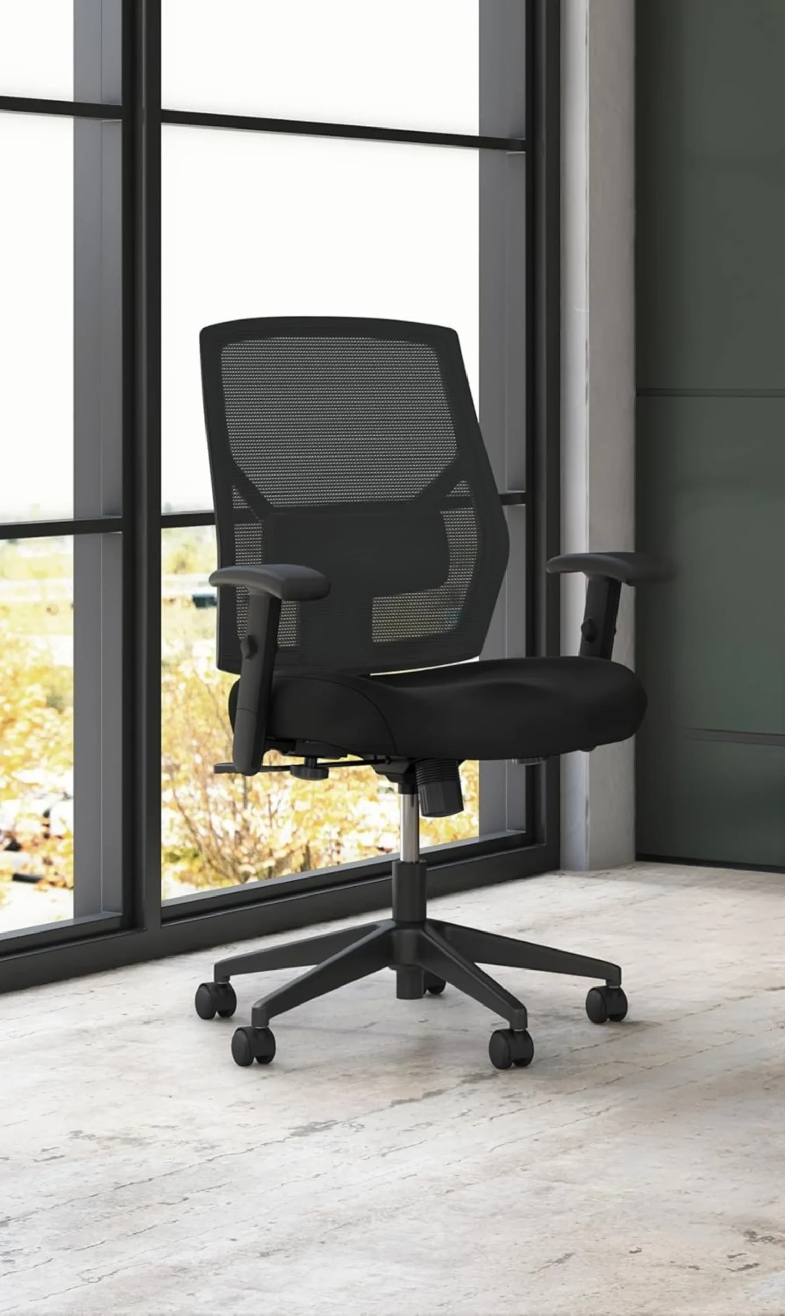 Black ergonomic mesh office chair with adjustable armrests and rolling base in a modern workspace